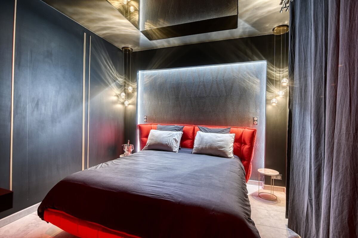 Chambre avec lit king size, tête de lit lumineuse et rideaux gris