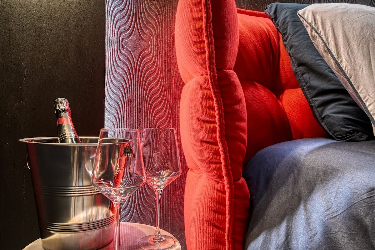 Chambre aux tons chauds avec tête de lit rouge et coussins en velours
