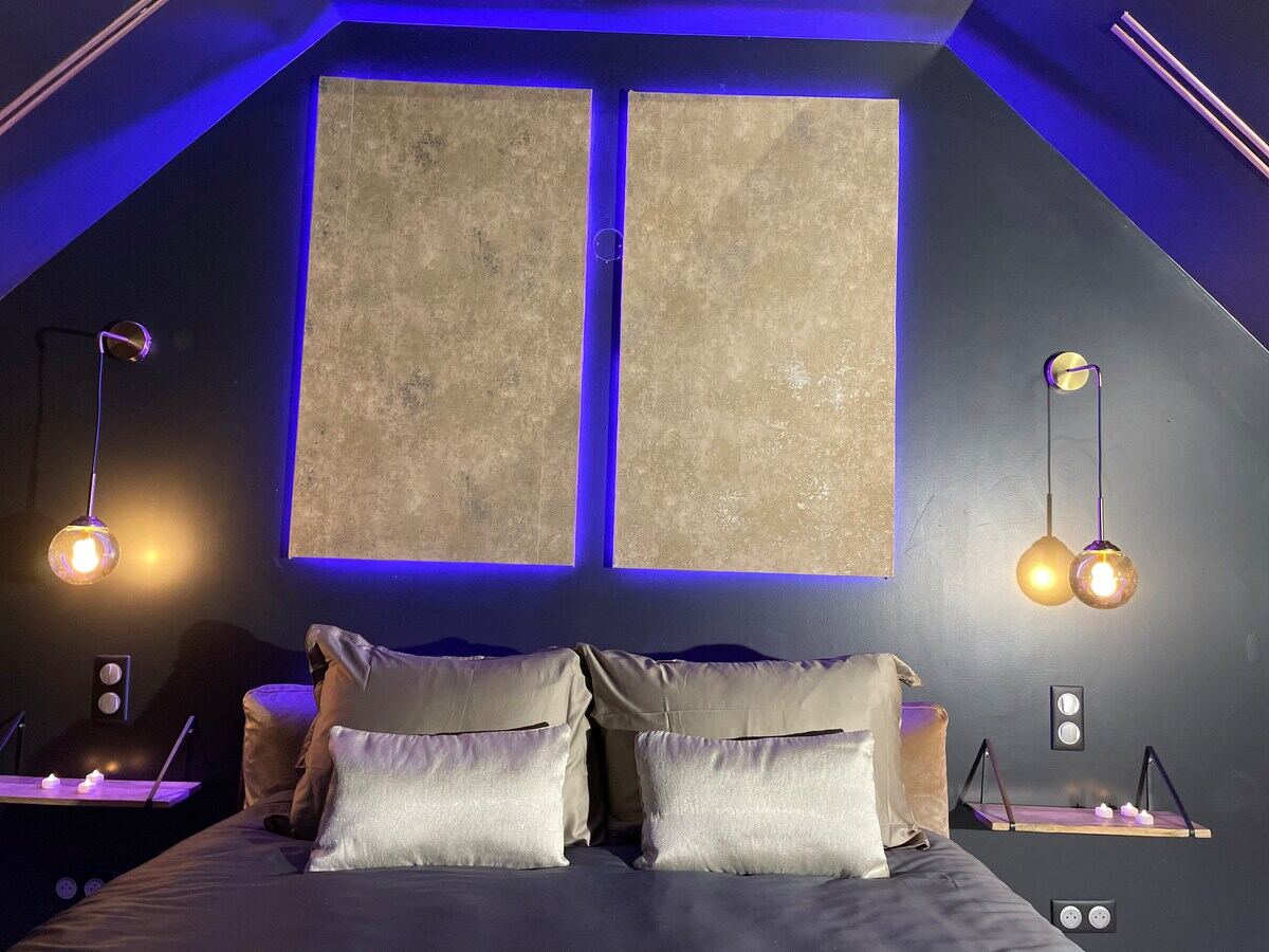 Chambre mansardée aux lumières bleues avec coussins dorés